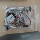 Průhledný plastový sáček s elektroinstalací pro hudební nástroj, obsahující bílé a červené vodiče, potenciometry a elektronickou desku. Na jedné z ko…