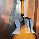 Zadní strana polodublové elektrické kytary s barevným přechodem od žlutého středu k černým okrajům (sunburst). Kytara má lakovaný povrch s viditelnou…