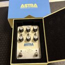 Stříbrný efektový pedál s nápisem ASTRA MODULATION MACHINE v krabici s pěnovou výplní. Na pedálu jsou šest otočných knoflíků a dva spínače s popisky…