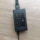 Černý spínaný adaptér s nápisem SWITCHING POWER SUPPLY. Na štítku je uveden MODEL 5024AMP1202000, INPUT 100-240V~ 50/60Hz 0.8A a OUTPUT 12.0V == 2.0A…