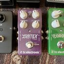 Tři kytarové efekty v řadě. První je černý pedál s nápisem GAIN a knoflíkem. Druhý je fialový pedál s nápisy VORTEX FLANGER a tc electronic, vybavený…