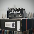 Černý kytarový efekt s nápisem Marshall, vybavený pěti ovládacími knoflíky. Na zadní straně jsou viditelné konektory Input a Output, vstup pro napáje…