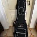 Černý polstrovatý obal na hudební nástroj s šedým lemováním a dvěma zipovými kapsami. V horní části je umístěno žluté logo a nápis soundsation. Obal…