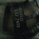 Detail kovového rámu reproduktoru s tmavým, patinovaným povrchem. Na kovu jsou vyrazeny dvě řady čísel: 064121 a pod nimi 137 7422. Povrch vykazuje z…