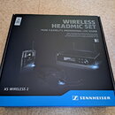 Fotografie krabice s nápisem WIRELESS HEADMIC SET a logem SENNHEISER. Na obalu je zobrazen bezdrátový mikrofon s hlavovou čelení, vysílač a přijímač.…