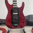 Elektrokytara s červeným lakovaným tělem a černým hmatníkem. Na černé pickguardu jsou dva snímače s nápisem "diMarzio" a kobylka typu Floyd Rose. V d…