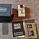 Na fotografii je kytarový efekt pedál krémové barvy s černým knoflíkem. Na pedálu jsou nápisy MXR, GAIN, OUTPUT a micro amp. Vedle efektu je černá kr…