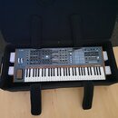 Šedý synthesizér s klaviatura uložený v černém přepravním pouzdle. Na horním panelu je vlevo nápis POLYBRUTE a vpravo nápis ARTURIA. Nástroj má dřevě…