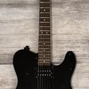 Černá elektrická kytara s tmavým hnedým hmatníkem a světlou dřevěnou hlavou. Na hlavě je viditelné logo Squier. Kytara má dva humbuckery, černý pickg…