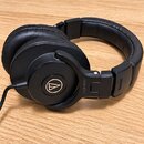 Černé náušlupnice s polovrchovou konstrukcí a koženým polstřením. Na vnější straně mušle je zlaté logo Audio-Technica a na rámu nápis ATH-M50x. Povrc…