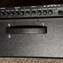 Černý kytarový kombo zesilovač s texturovaným povrchem. Na ovládacím panelu jsou nápisy KATANA 100, AMPLIFIER, EQUALIZER, EFFECTS, TONE SETTING a CAB…