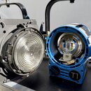 Dvě studiová světla s černými držáky. Levý reflektor je v černé barvě s nasazeným klapněm a vrchním sklem. Pravý reflektor je modrý, otevřený a uvnit…