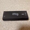 Černý obdélníkový audio rozhraní s nápisem iRig a označením HD 2. Na levé straně je vidět symbol mikrofonu a ikona baterie. Povrch zařízení je matný,…