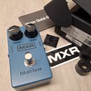 Modrý efekt pedál s nápisy MXR a blue box. Má dva černé ovládací knoflíky označené jako OUTPUT a BLEND, stříbrný spínací pedal a vstupy OUTPUT a INPU…