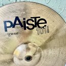 Kruhové činely z mosazi s viditelným broušením. Na povrchu je černý nápis Paiste 101 BRASS a menší text 13" HI-HAT TOP. Povrch vykazuje drobné škrába…