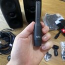 Ruka drží černý, úzký elektronický přístroj s nápisem ARC. Na horní části je vidět nápis FRONT a malá kontrolka, dále níže je nápis ON. V pozadí jsou…