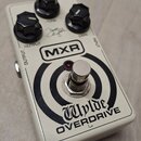 Bílý kytarový efekt MXR Wylde OVERDRIVE s černými oválnými knoflíky. Na horní straně jsou nápisy TONE, GAIN a OUTPUT, vedle nich je viditelný podpis.…