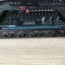 Černý sampler a kontroler s nápisem AKAI R8. Zařízení má horní panel s posuvníky, knoflíky a displejem. Na zadní straně jsou vstupy a výstupy s popis…