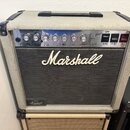 Kytarový zesilovač značky Marshall v krémovém vinylu s černou přední mřížkou. Na ovládacím panelu jsou knofíky a přepínače s nápisy: INPUT, GAIN, VOL…