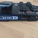 Černý kytarový pedál s expresním pedálem z kovové mřížky. Na boku je bílé logo LINE 6 a nápisy TO AMP OR POD u konektoru oraz USB u portu. Na horní s…