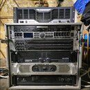 Sestava rackového audio vybavení v kovovém case. V horní části je umístěn zesilovač značky Crown a pod ním zařízení s označením BE-2000. V racku se n…