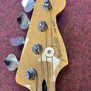 Hlava basové kytary z přírodního dřeva s čtyřmi chromovanými ladičkami. Na povrchu je čitelně napsáno logo Fender® a název modelu JAZZ BASS®. Povrch…