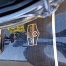 Detailní záběr na černý, lesklý povrch bubnu s kovovým logem ve tvaru štítu. Na logu je doslovně uveden nápis TAMA IMPERIALSTAR a menší text MADE IN…