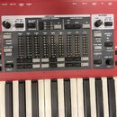 Detailní pohled na ovládací panel červeného elektronického orhanu s klávesami. Panel obsahuje sekce ORGAN, PIANO a PROGRAM s různými přepínači, posuv…