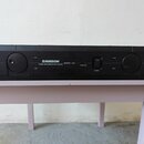 Černý rackový zesilovač s nápisem SAMSON STUDIO AMPLIFIER 85 WATT STEREO SERVO-170. Na předním panelu jsou dvě velké otočné potenciometry, vypínač PO…
