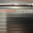 Černý přijímač bezdrátového mikrofonu s kovovou anténou. Na přístroji je nápis RH SOUND v červené barvě a text Wireless Mic. Receiver Diversity WR-10…