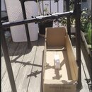 Černý kovový stojan na bicí nástroje s několika nastavitelnými rameny. Vedle stojanu je otevřená kartonová krabice s nápisem DRUM STAND. Celý komplet…