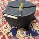 Černý plastový přepravní kufr značky HARDCASE. Na boku je nalepená bílá nálepka s nápisem HIGHLAND a malý žlutý štítek s textem HARDCASE MADE IN THE…