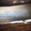 Detailní záběr na papírovou nálepku uvnitř hudebního nástroje. Na štítku je v gotickém písmu text: „am Martin macht mich in Reutlingen, in Baigh land…