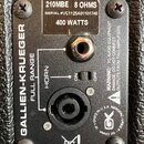 Detail zadní strany reproduktorové skříně značky GALLIEN-KRUEGER. Na horním štítku je uveden model 210MBE, impedance 8 OHMS, sériové číslo SERIAL #VC…
