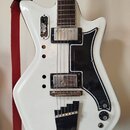 Bílá elektrická kytara s černým plechtrátem. Na těle jsou dva humbuckery, jedna tónová klika a dvě potenciometry s nápisy Volume a Tone. V horní část…