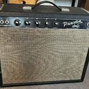 Kytarový zesilovač v černém krytu s béžovou textilní mřížkou. Na ovládacím panelu je nápis Princeton Amp a Fender Electric Instrument Co., dále označ…