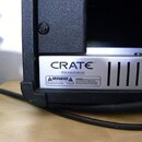 Detail zadní části černého kytarového komba s texturovaným povrchem. Na stříbrném kovovém panelu je černý nápis CRATE® a pod ním text PATENT #5,032,7…