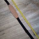 Černý popruh na hudební nástroj s hnědým koženým polstrováním v středové části. Popruh má na koncích šedé plastové úchyty pro upevnění k nástroji. Ve…