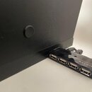 Černý USB hub značky BELKIN s pěti porty. Povrch zařízení vykazuje viditelné opotřebení a oděrky v horní části. Hub je připojen k černému zařízení.
