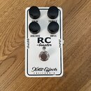 Bílý kytarový efekt s nápisy RC -booster a Xotic Effects CALIFORNIA. Na horní straně jsou čtyři černé otočné knoflíky s popisky GAIN, TREBLE, VOLUME…
