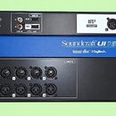 Černý rackový systém s modrým panelem uprostřed. Na horním panelu je nápis AFS2 a čtyři AUX OUTPUTS, vlevo konektory MIDI, PLAY, REC a USB s nápisem…