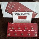 Červený přepínač efektů s nápisem OCTA-SWITCH MK3. Na spodní straně jsou uvedeny texty MADE BY EAST SOUND DENMARK a DESIGNED BY THOMAS GULDMANN. K za…