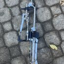 Chromykovaný kovový mechanismus pedálu k bicím sadě. Na komponentu nejsou viditelné žádné značky ani nápisy. Povrch je lesklý, s viditelnými stopami…
