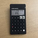 Černý přenosný syntezátor s nápisem pocket operator. Displej zobrazuje grafiku dvou postav, text K.O! a označení PO6. Zařízení má numerickou klávesni…