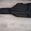 Černý polstrovatý pouzdro (gig bag) na kytaru s dvěma ramenními popruky a horní rukojetí. Povrch je z černé látky s prošíváními. Na pouzdře nejsou vi…