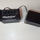 Černý kytarový zesilovač Blackstar s oddělenou hlavou a reproduktorem. Na ovládacím panelu jsou nápisy FLY, GAIN, VOLUME, EQ, DELAY a POWER spolu s l…
