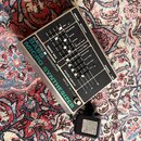 Stříbrný efektový pedál s nápisem ELECTRO HARMONIX BASS MICRO SYNTHESIZER a MADE IN USA. Zařízení má několik posuvníků s popisy jako TRIG, SUB OCTAVE…