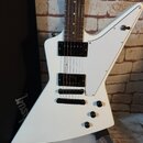 Bílá elektrická kytara s asymetrickým tělem a hnědým hmatníkem. Nástroj má dva černý humbuckery, jeden černý knoflík hlasitosti a dva přepínače. Na t…