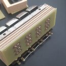Fotografie zachicuje elektronickou součástku, pravděpodobně část syntezátoru nebo efektového pedálu. Skládá se z vrstveného dřevěného nebo laminátové…