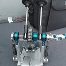 Krytý kovový mechanismus s dvěma vertikálními pákami zakončenými černými pěnovými molitovými kryty. Zařízení je provedeno v kombinaci stříbrného a mo…